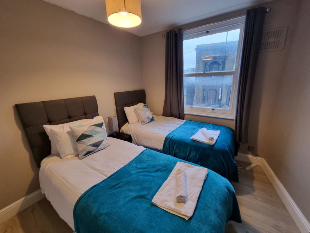Logement lumineux ayant éte récemment entiérement rénové et disposant d’une chambre double et d’une chambre Twin (avec 2 lits simples), de taille convenable. – Appartement moderne situé au centre du quartier de Bow/Mile End avec un parc tout proche du logement (à moins de 5 mn à pied). – Accés facile pour se rendre dans le centre ville en moins de 15 mn, mais aussi dans le quartier de Stratford en 10 mn ou le Sud de Londres grâce au DLR ou en Bus, dans des quartiers comme Canary Wharf ou Greenwich. Logement bien situé à ce niveau. – L’appartement dispose d’un salon entiérement séparé avec TV, sofa, table et chaises, d’une cuisine séparée totalement équipée et d’une salle de bain avec Baignoire. – Cet appartement de 2 chambres peut loger jusqu’à 4 personnes. Il est situé au 1er étage d’un petit immeuble.